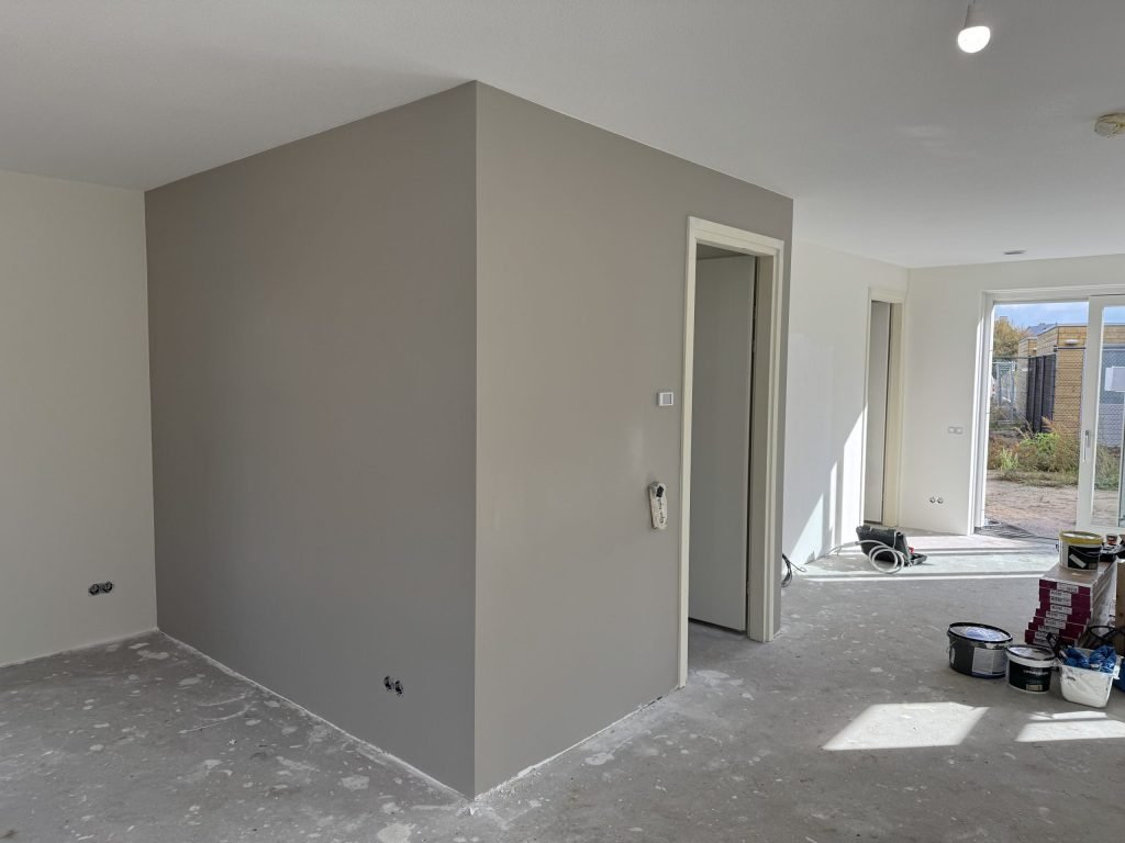 Woning met een pas afgewerkte grijze wand en verfemmers op de vloer